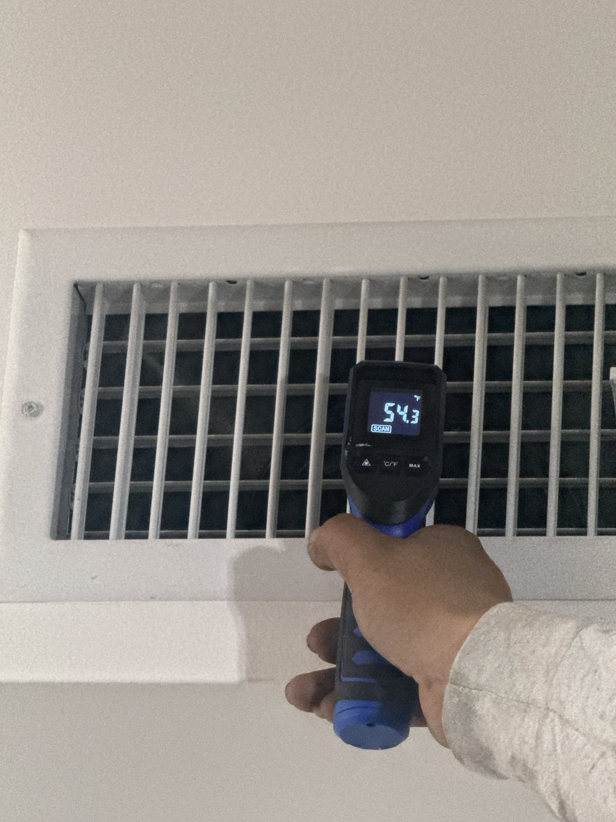 Infrared thermometer reading 54.3 degrees Fahrenheit at an AC supply register.